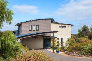 A modern two-story house with a curved roof, a covered driveway, and a landscaped garden. - “ROCKPOOL” Holiday Beach House Margaret River (5 bedrooms,  walk to beach) (Gnarabup)