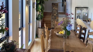A modern kitchen with white cabinets, a built-in refrigerator, and a dining area with wooden chairs and a table. - “ROCKPOOL” Holiday Beach House Margaret River (5 bedrooms,  walk to beach) (Gnarabup)