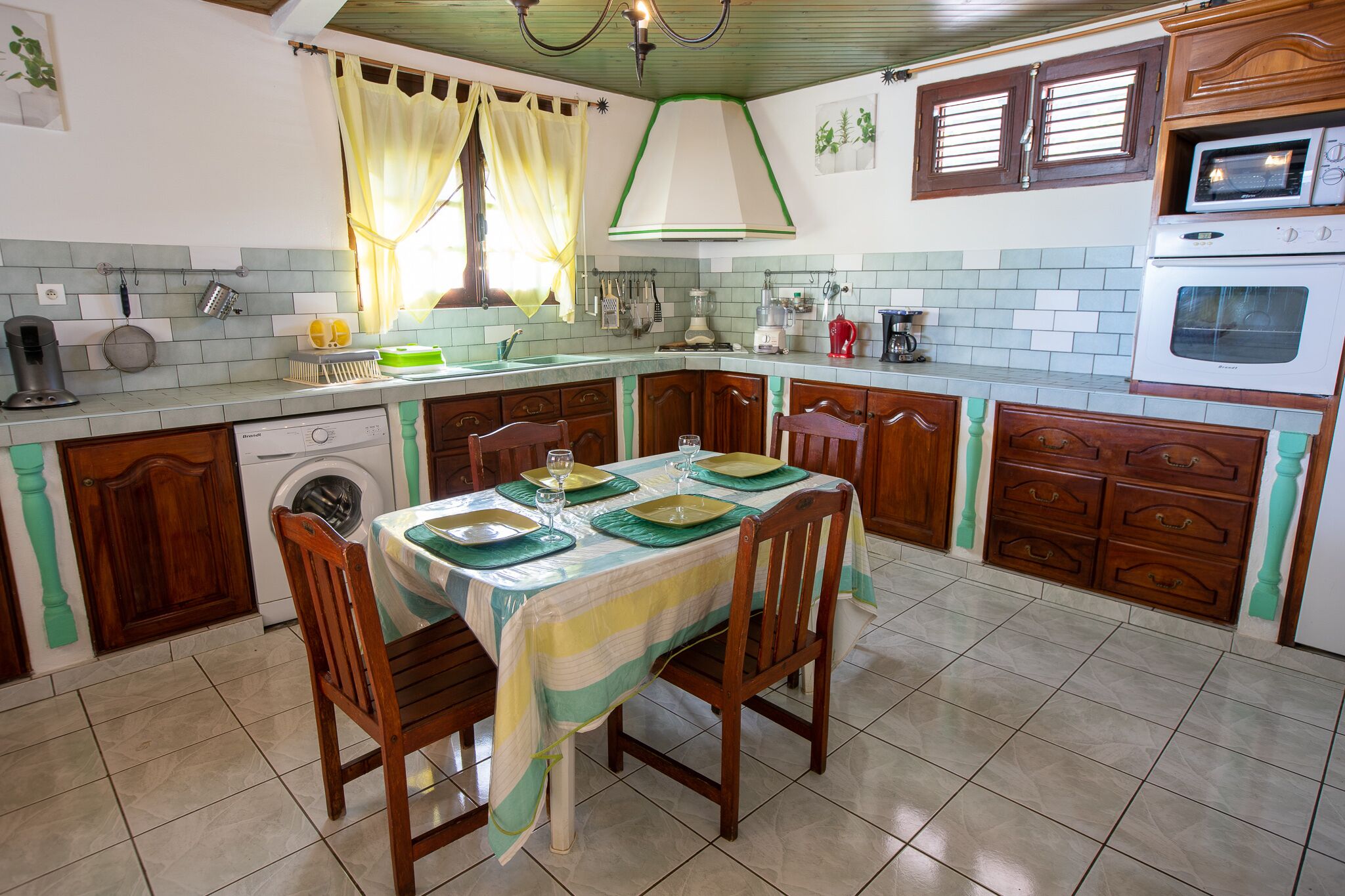 Una cocina con una mesa de comedor para cuatro personas, una lavadora y un microondas.