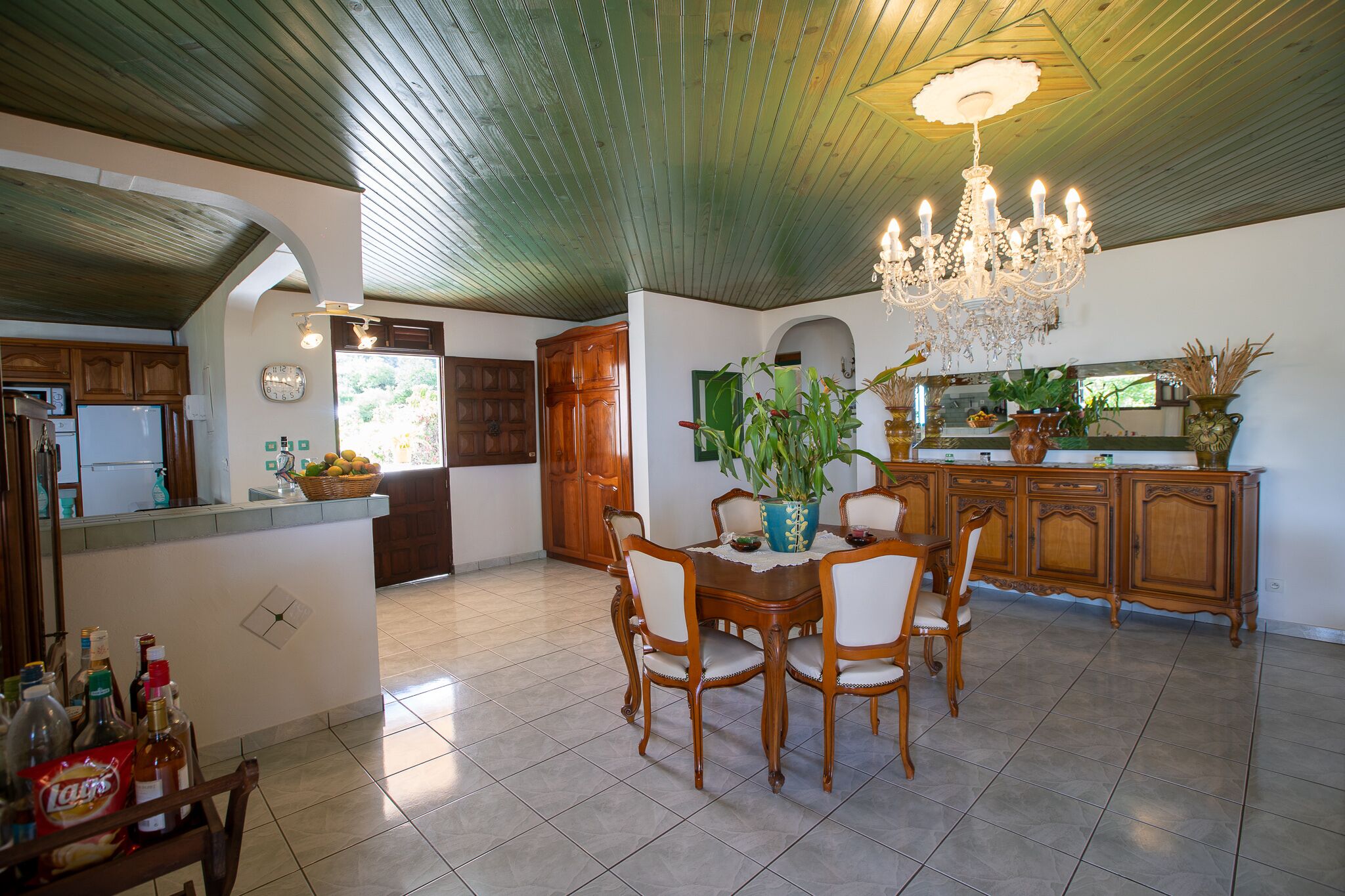 A spacious kitchen with wooden cabinets, a dining table with chairs, and a chandelier.