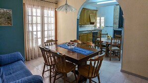 Un coin repas avec une table et des chaises en bois, un set de table bleu et un luminaire suspendu.