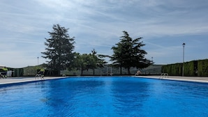 Une piscine équipée de bouées de sauvetage, entourée d’arbres et d’une haie.
