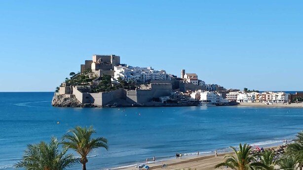 Une ville côtière dotée d’un château fortifié situé sur une petite île, entourée d’eaux bleues et cristallines et bordée d’une plage de sable.