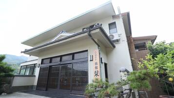 A building with a large black gate, a sign with Japanese characters, and a potted plant in the foreground.