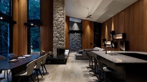 Una cocina moderna con chimenea de piedra, paneles de madera y una isla grande con pileta.