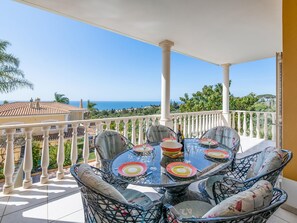 A balcony with a table set for dining, overlooking a scenic view of the sea and greenery. - Casa Mira Luz, villa with private pool (Praia da Luz)