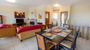 A dining area with a table set for four, a sofa, a television, and a fireplace. - Casa Mira Luz, villa with private pool (Praia da Luz)