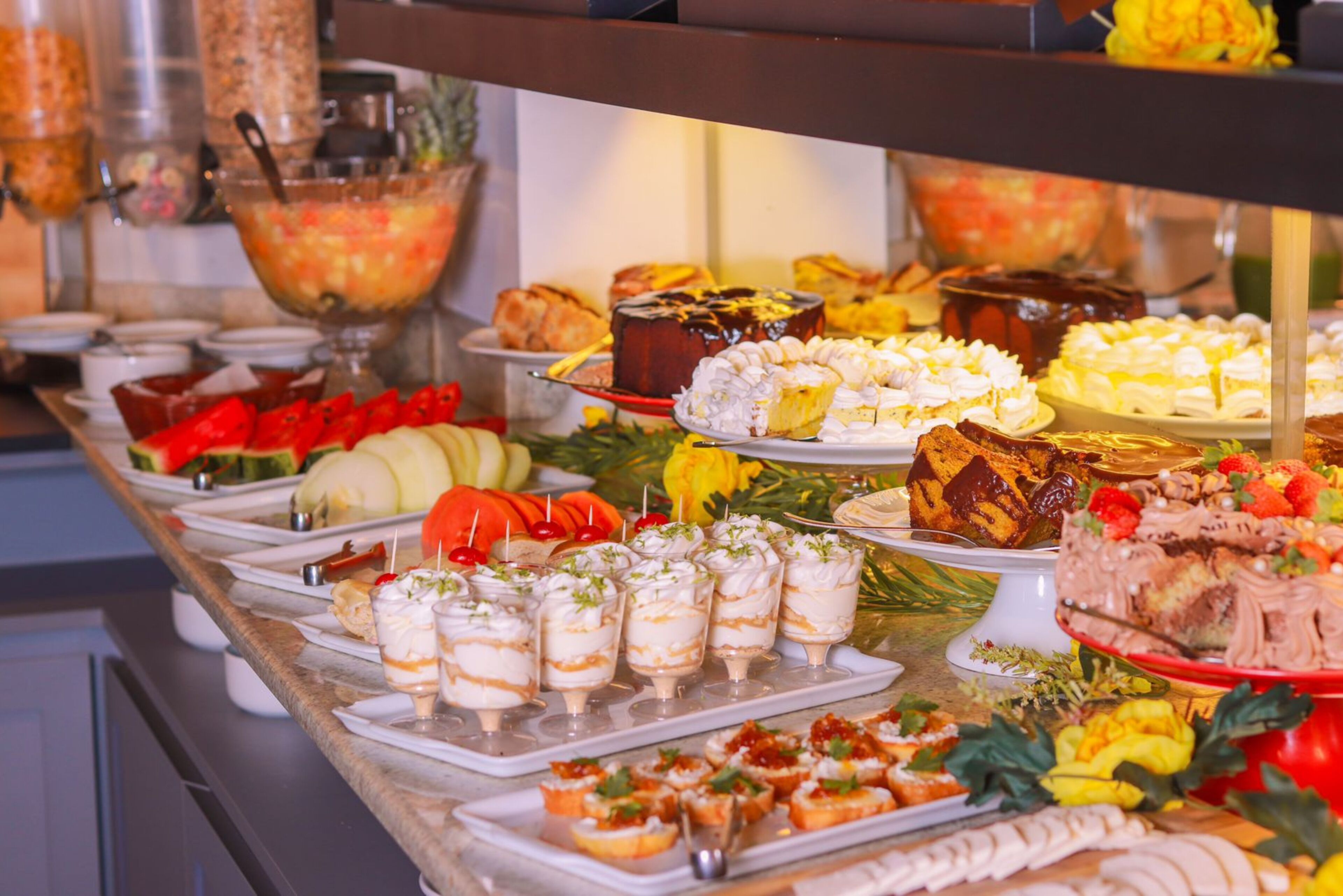 Un bufé con diversos platos, incluyendo postres, frutas y aperitivos.