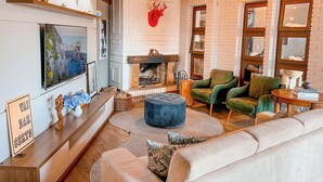 A cozy living room with a fireplace, comfortable seating, and a television on the wall. - Flame Boutique Hotel by Unna (Canela)