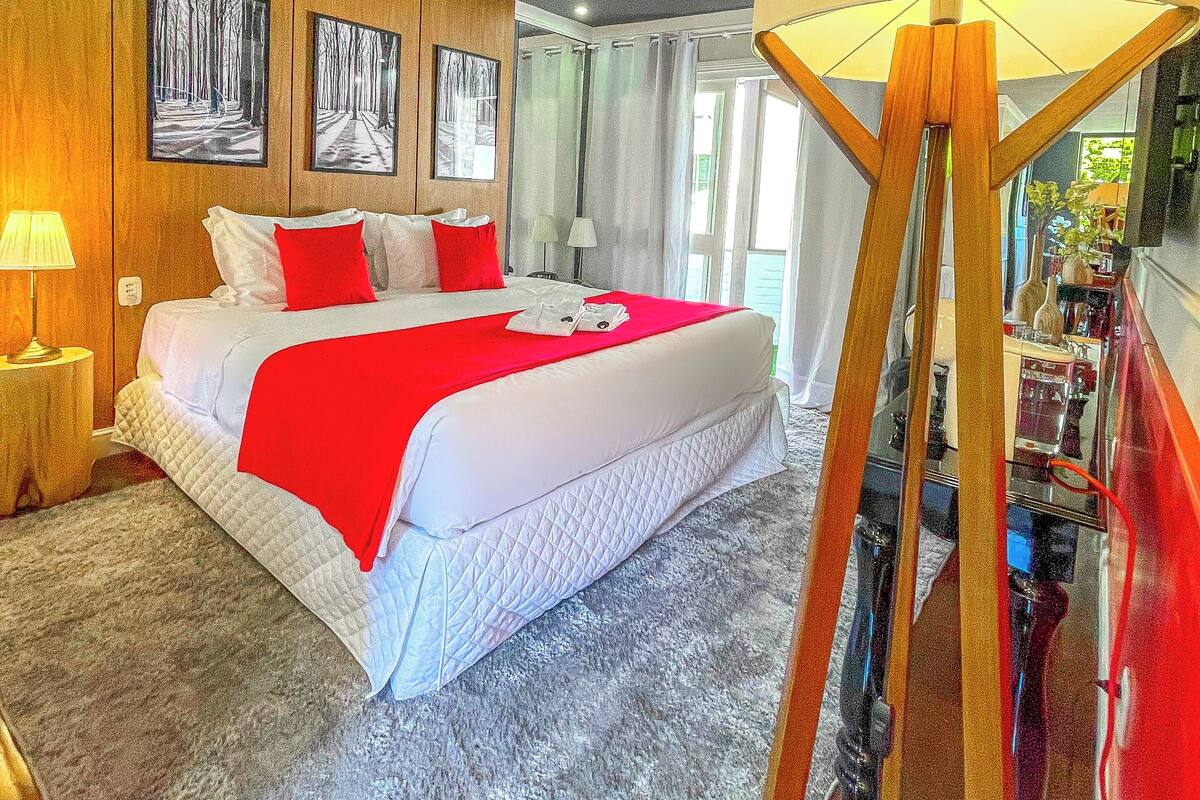 A hotel room with a large bed, wooden panel walls, and a view of the outdoors.