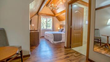 A bedroom with a wooden ceiling, a bed, a desk, and a window.
