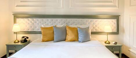 A neatly made bed with a tufted headboard, two bedside tables with lamps, and a patterned throw blanket.