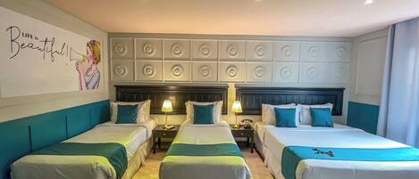A hotel room with three single beds, a large mirror, and a decorative wall with a motivational quote.