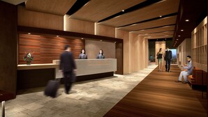 Et moderne receptionområde med en træreception, et loungeområde med sofa og et gulv med et fisbenmønster.