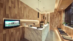 A modern reception area with a wooden wall, a marble counter, a flat-screen TV, and a seating area with cushions. - Shanghai Annshe Hotel (Shanghai)