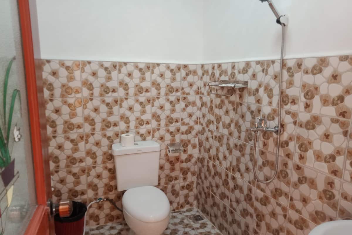 Une salle de bain avec des toilettes, une douche et des carreaux décorés.