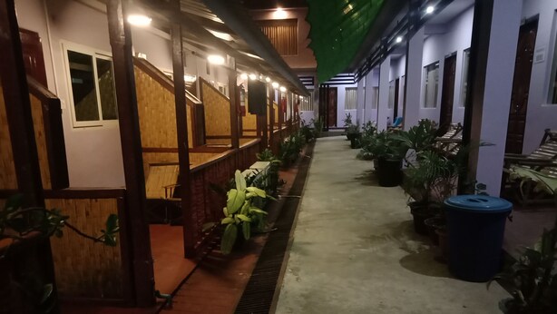 A corridor with wooden partitions, potted plants, and a blue trash bin.