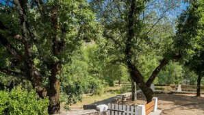 A park with a stone wall, a wooden bench, and a white picket fence. - Cottage with River Views, Uzer (Uzer)