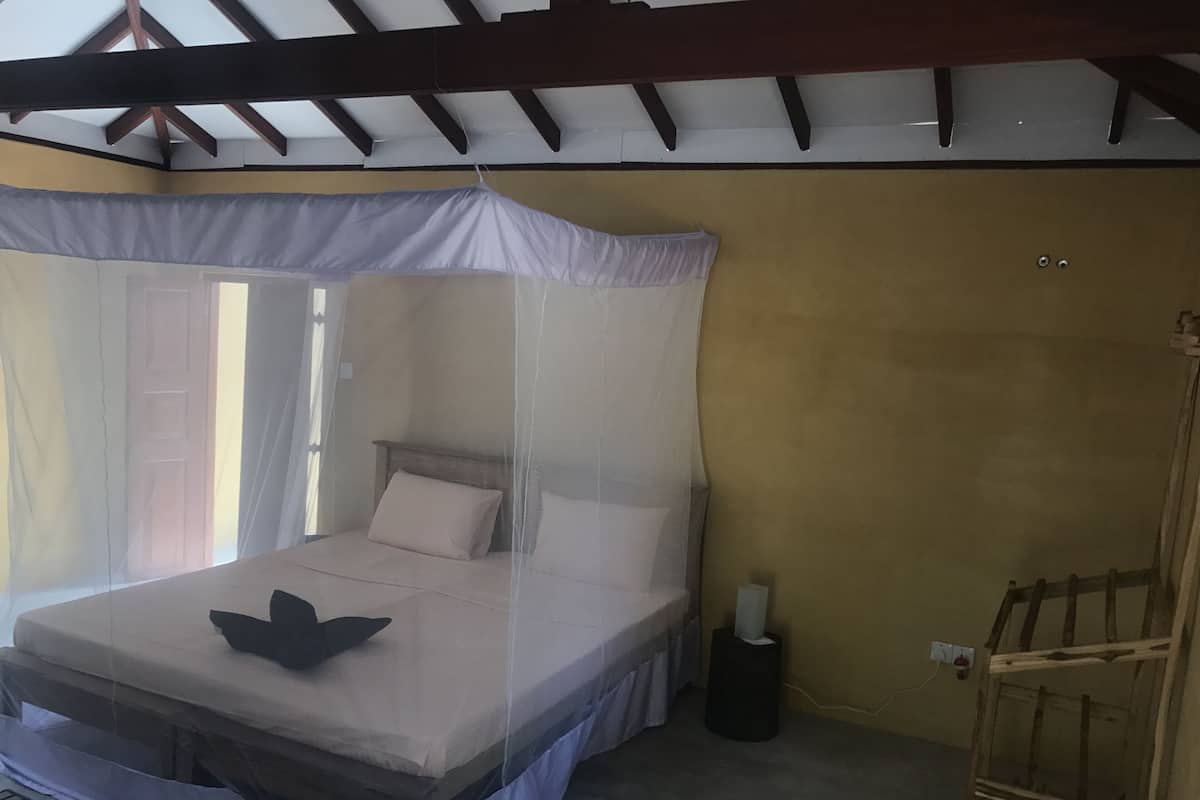 Una cama individual con dosel, una mesita de noche y un aplique de pared.
