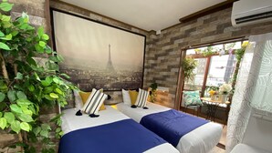 A hotel room with two beds, a mural of the Eiffel Tower, a brick wall, and a balcony with plants. - Orange House (Osaka)