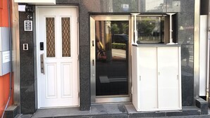 A building entrance with a white door, a glass door, and a small window. - Orange House (Osaka)