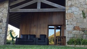 Una casa moderna con fachada de piedra, una terraza de madera y un área de estar exterior en color negro.