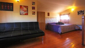 Una habitación con cama, sofá, piso de madera y luces fijadas a la pared.