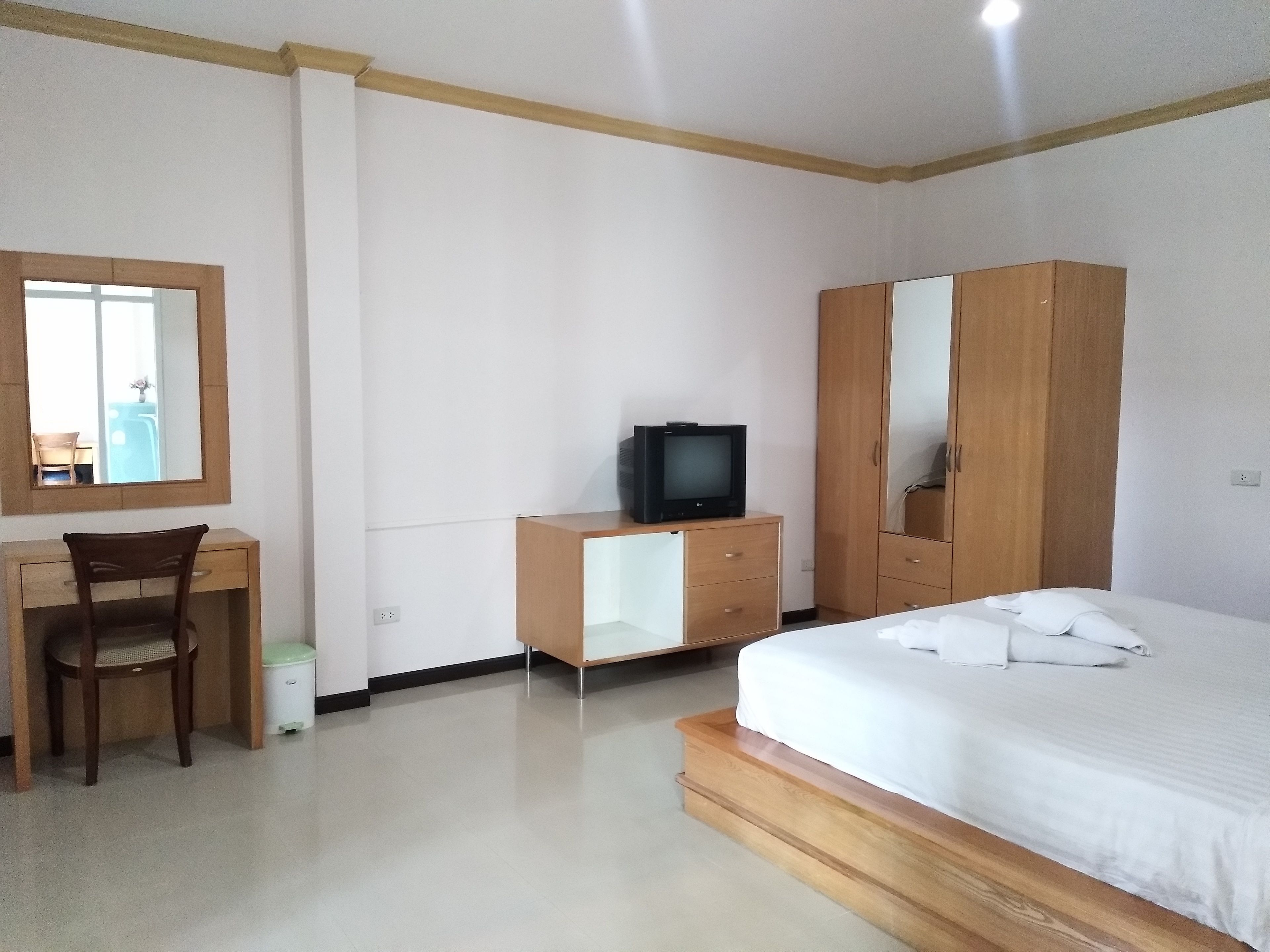 Un dormitorio con cama, escritorio con silla, armario y televisor.