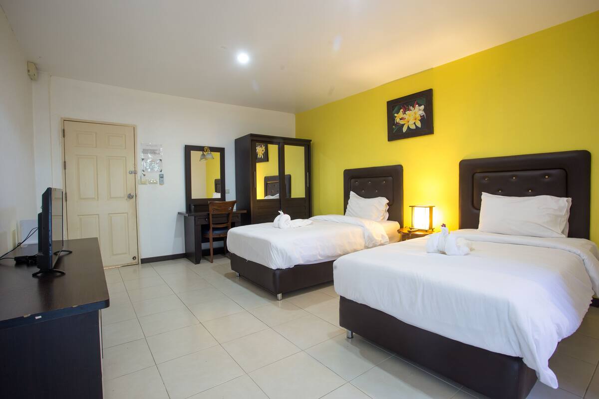 A hotel room with two beds, a desk, a chair, a mirror, and a picture on the wall.