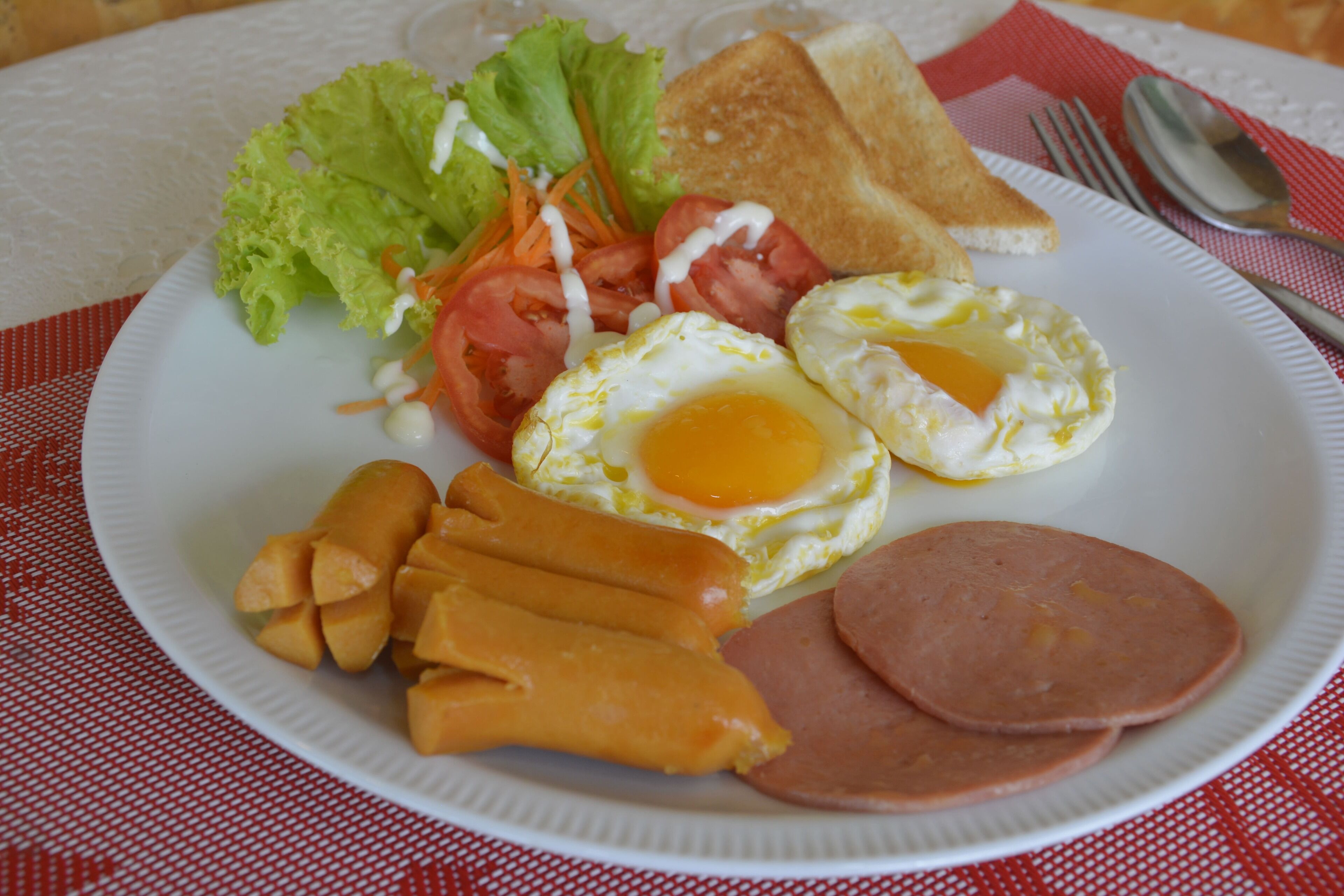 A plate of food with eggs, ham, and vegetables.