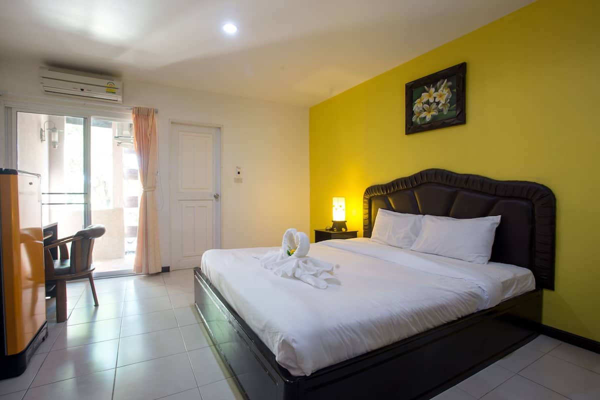 A hotel room with a bed, a desk, a chair, a lamp, and a painting on the wall.