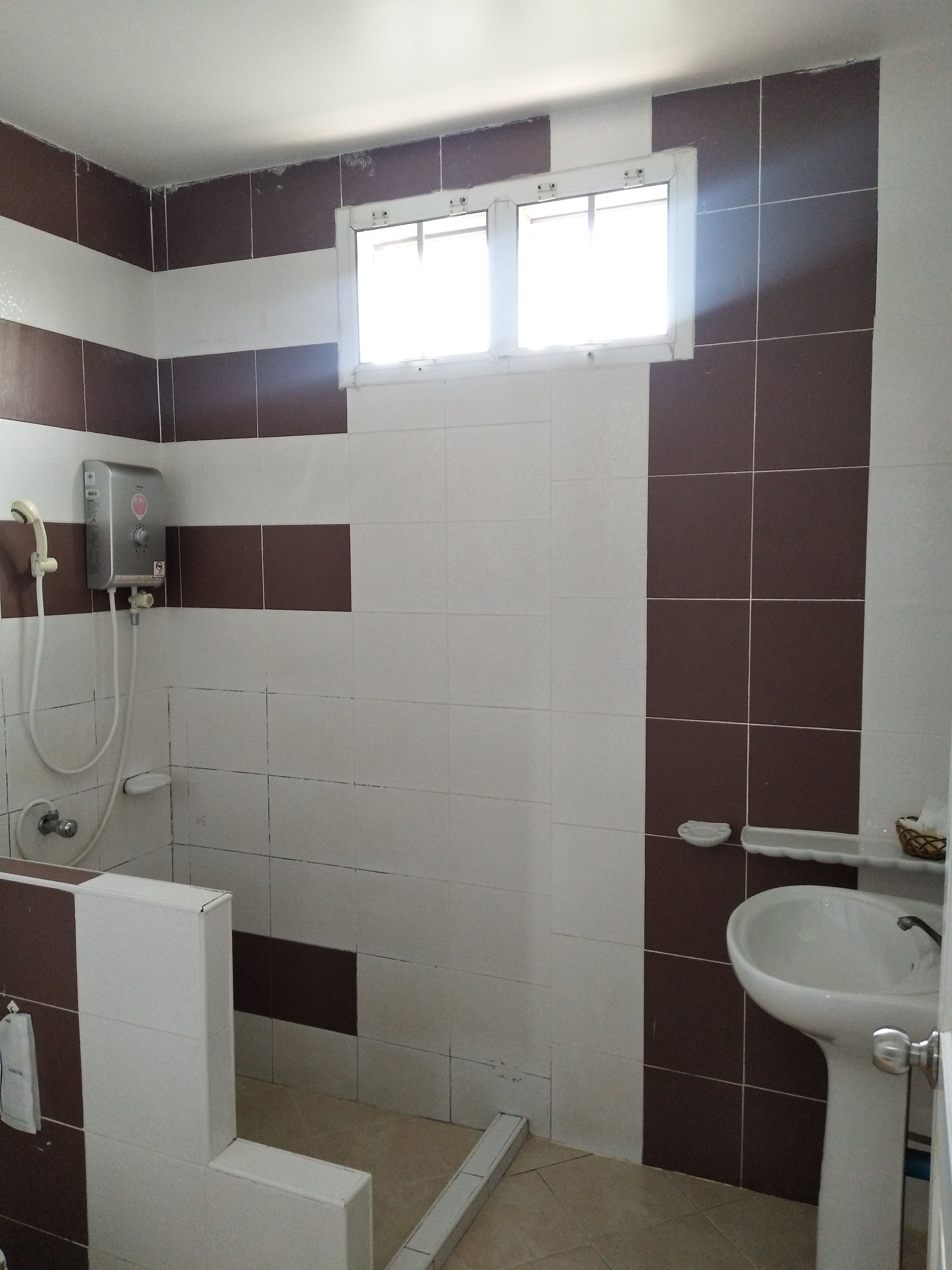 A bathroom with a shower, a sink, and a window.