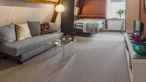 Een moderne woonkamer met een grijze bank, een glazen salontafel en een houten balk.