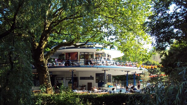 Een meerlaags gebouw met terrassen, omringd door bomen.