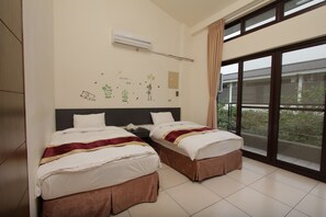 Habitación de hotel con dos camas, un ventanal grande y un equipo de aire acondicionado en la pared.