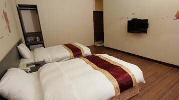 A hotel room with two beds, a mirror, a TV, and a small shelf with toiletries.