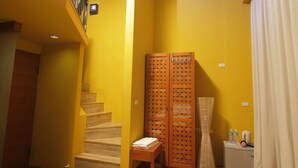 A staircase leading to a second floor, a wooden wardrobe with a lattice design, a small wooden table with a towel, and a white cabinet with toiletries. - Sanyi Sakura Resort (Sanyi)