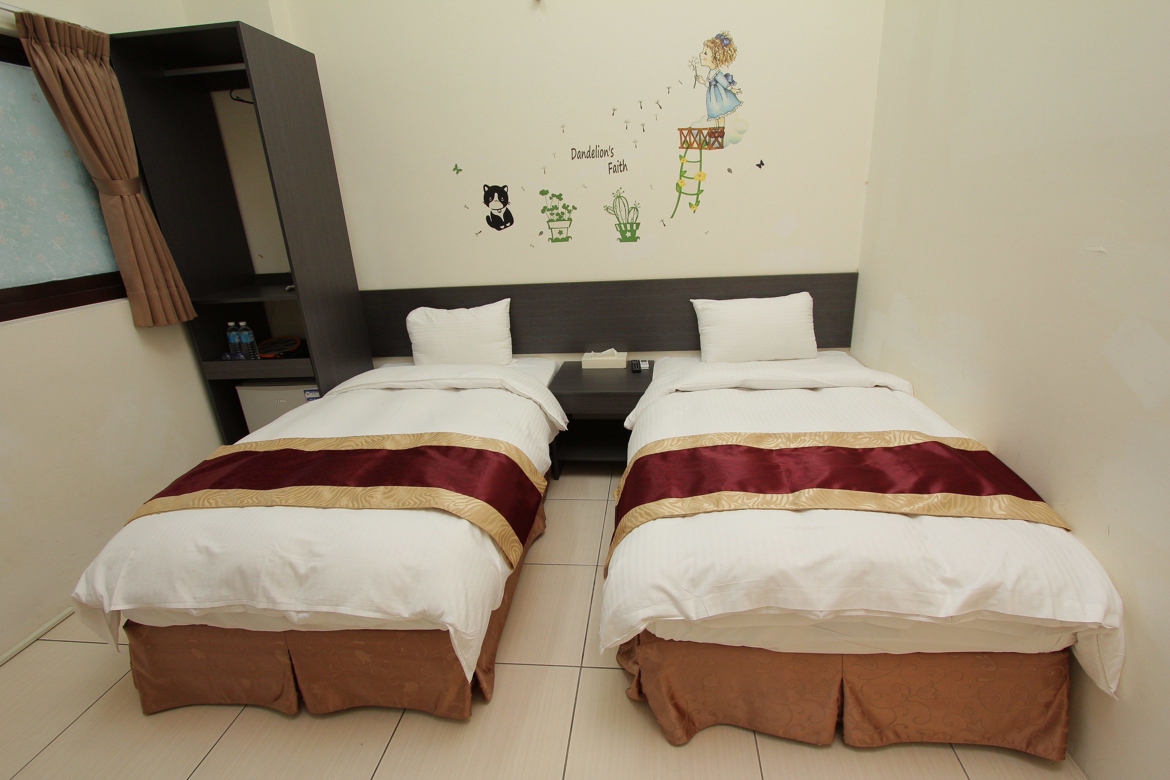 Quarto de hotel com duas camas, um guarda-roupa e um adesivo na parede.