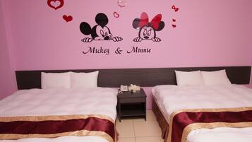 A hotel room with two beds, a nightstand with a phone, and a wall decoration featuring Mickey and Minnie Mouse surrounded by hearts.