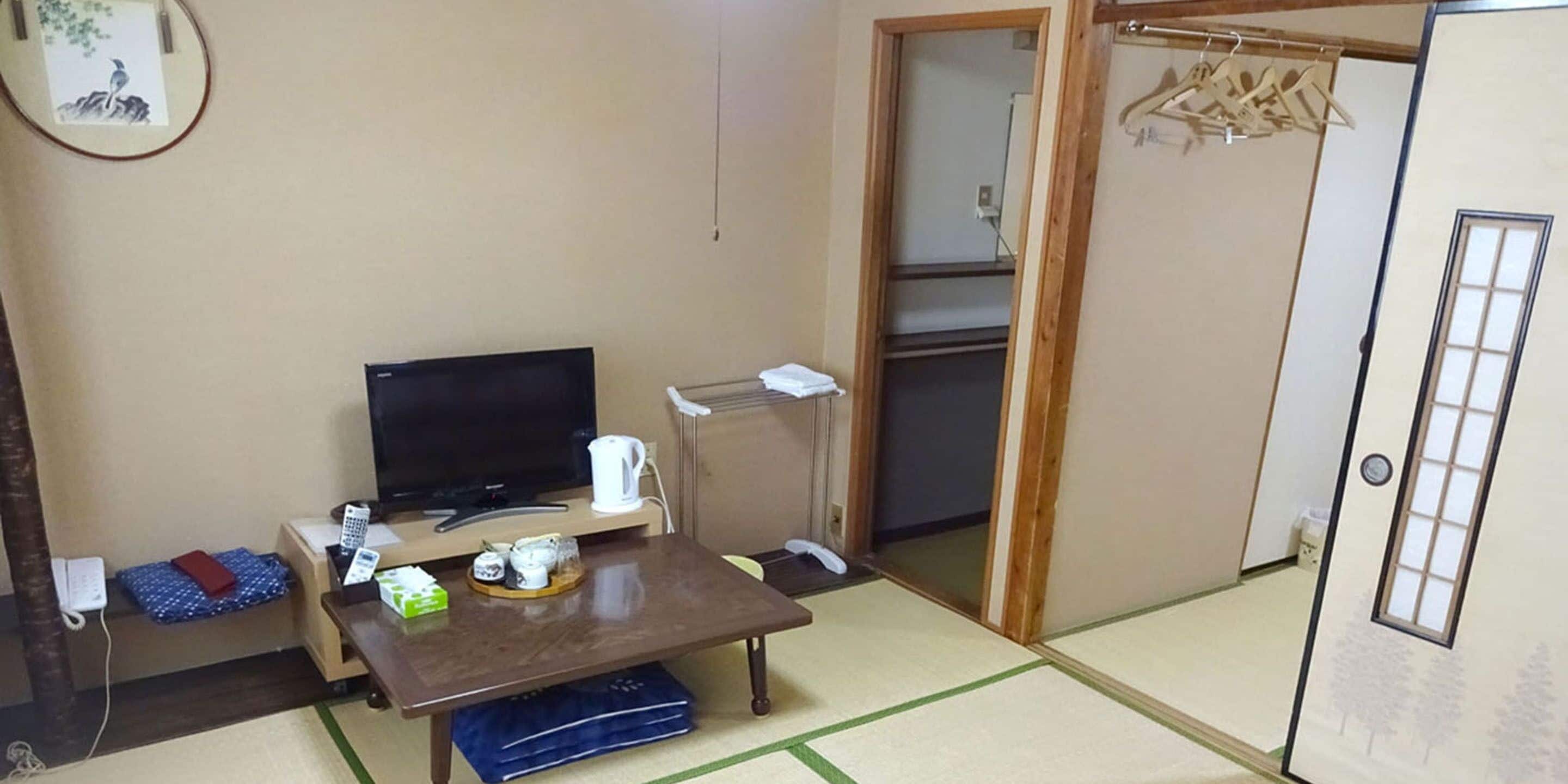 A small room with a TV, a table, a sofa, and a wardrobe.