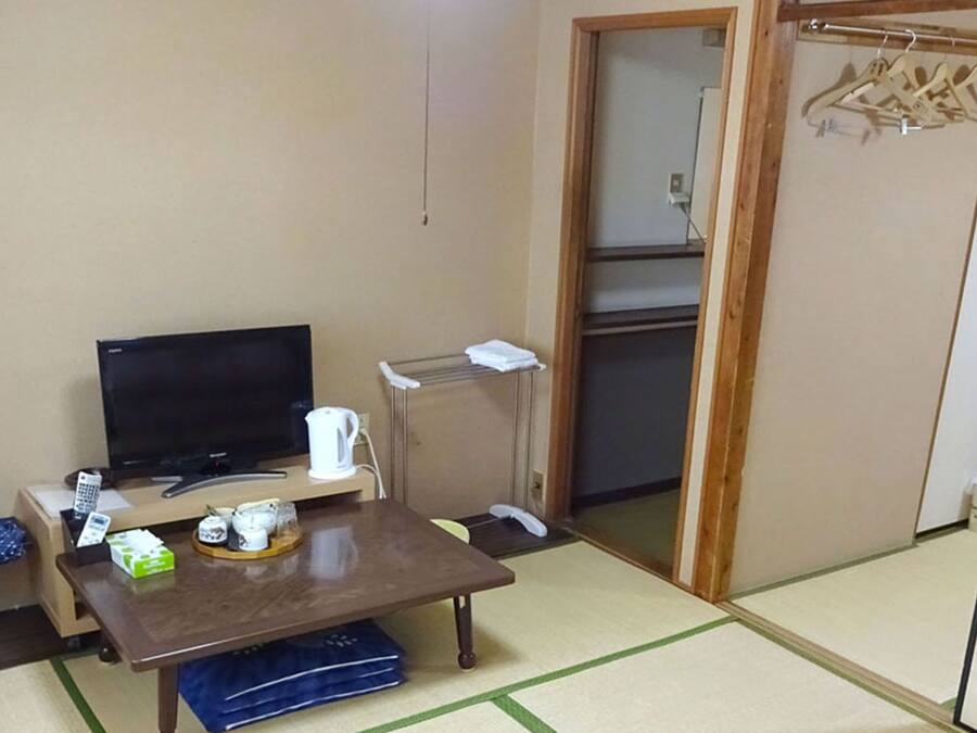 A small room with a TV, a table, a sofa, and a wardrobe.