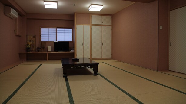 A traditional Japanese room with tatami flooring, a low table, a television, sliding doors, and a window with shoji screens. - Imazato Ryokan (Osaka)