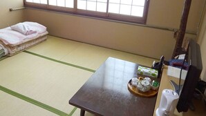 A tatami mat room with a bed, a table with tea sets, and a window. - Imazato Ryokan (Osaka)