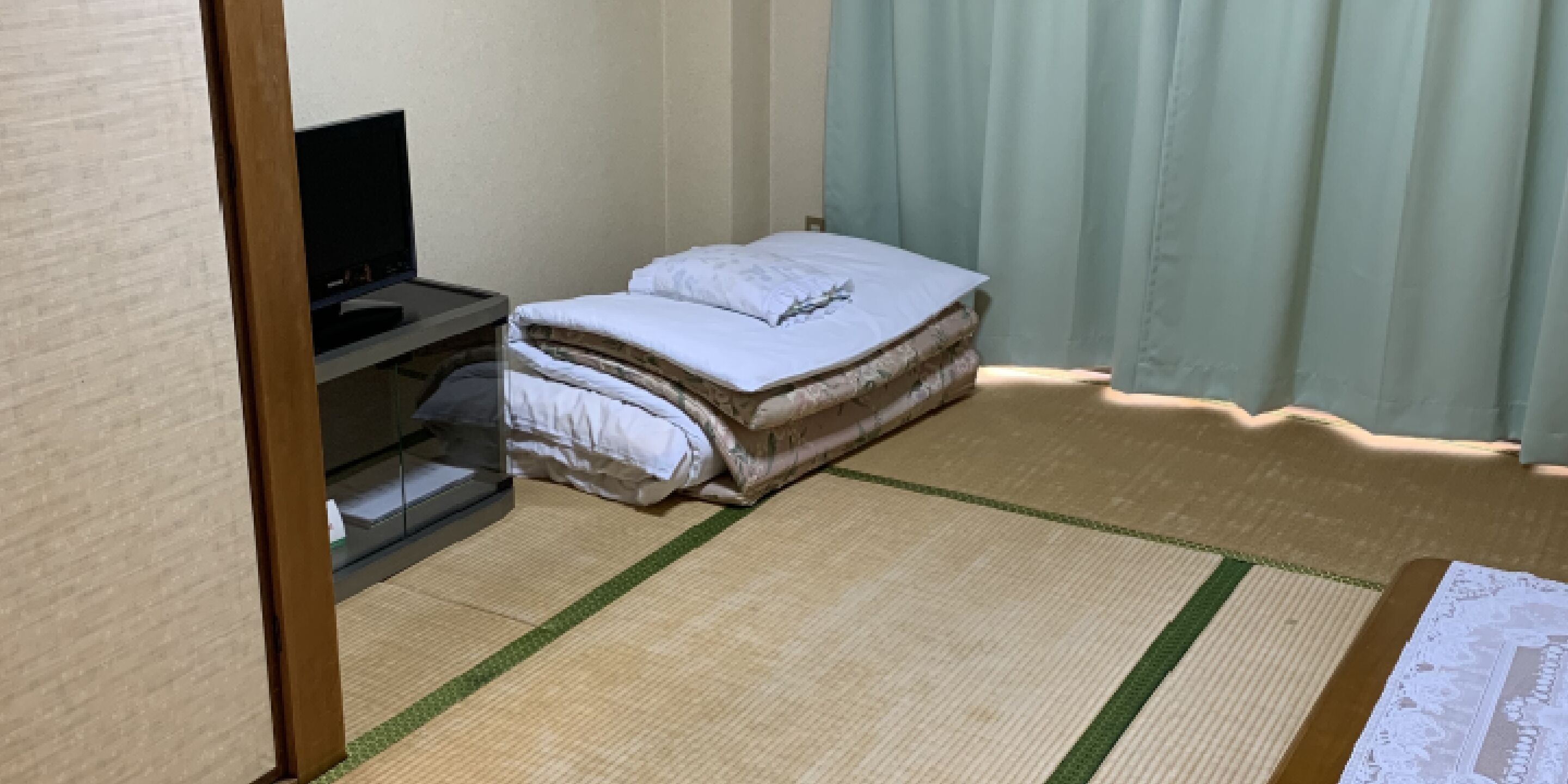 A bedroom with a bed, a desk, and a television.