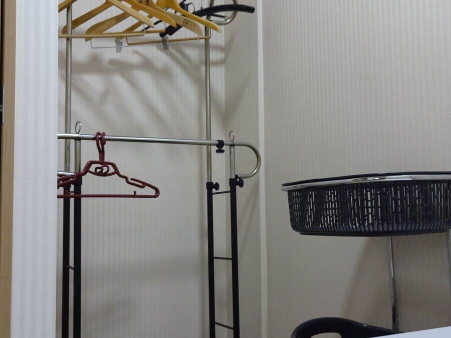 Um armário pequeno com um esguicho de metal, uma cesta de armazenamento preta e piso de azulejos.