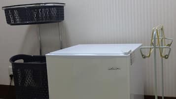 A compact white refrigerator with a brand label, a black woven basket, and a metal stand with hooks.