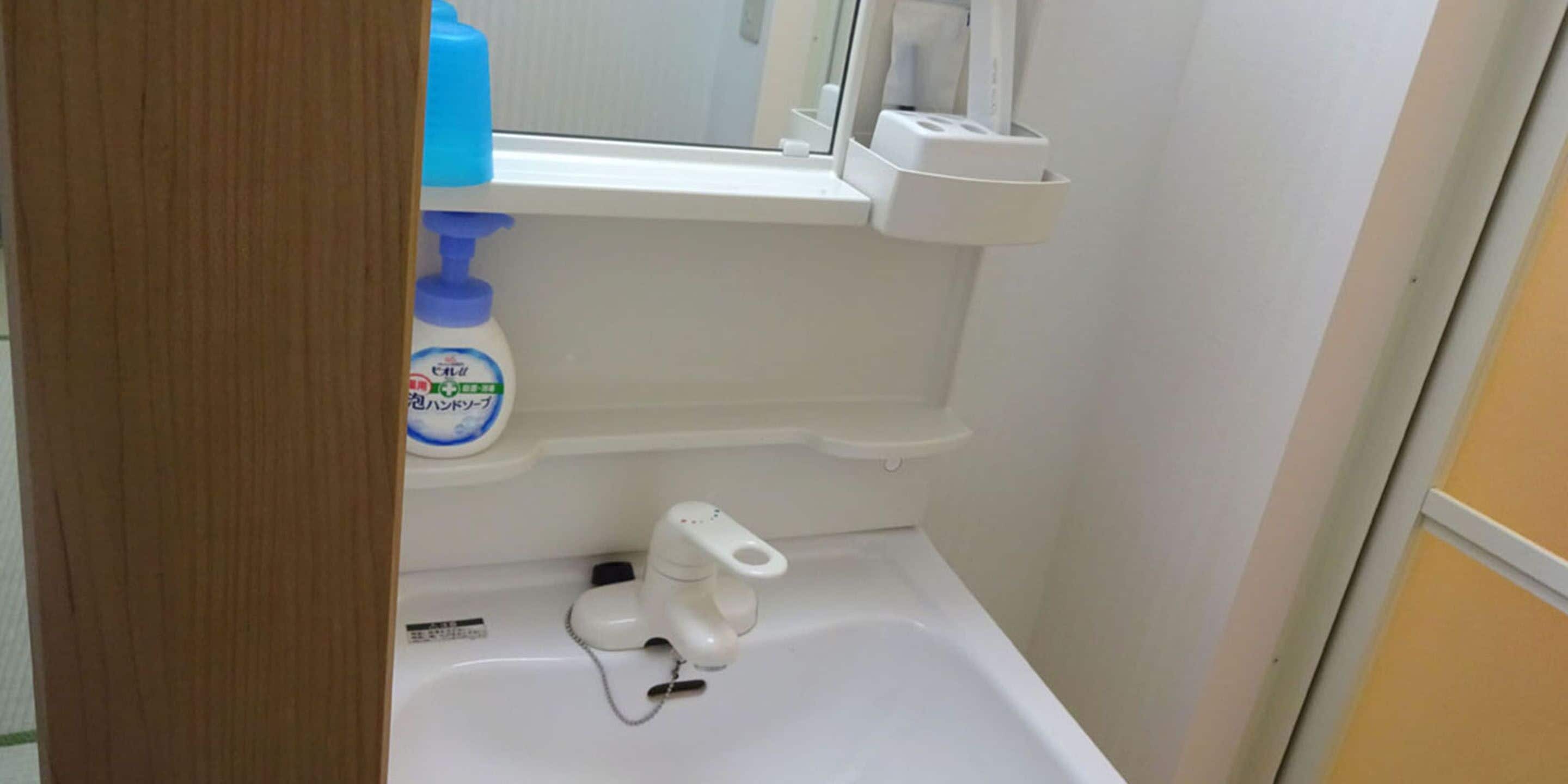 Un bagno con lavandino bianco, uno specchio e una finestra.