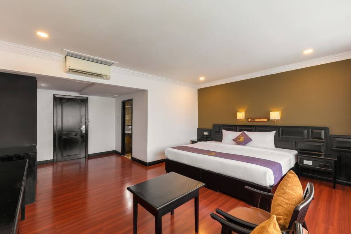 Ein Hotelzimmer mit Bett, Schreibtisch, Stuhl, Kleiderschrank und Tür.