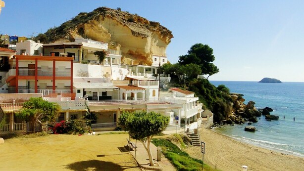 A coastal building with multiple balconies overlooking the sea, a sandy beach, and rocky outcrops. - Enjoy and relax with the light, the murmur of the sea and the fantastic views (San Juan de los Terreros)