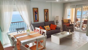 A living room with a sofa, two chairs, a table, and a balcony with a view of the sea. - Enjoy and relax with the light, the murmur of the sea and the fantastic views (San Juan de los Terreros)